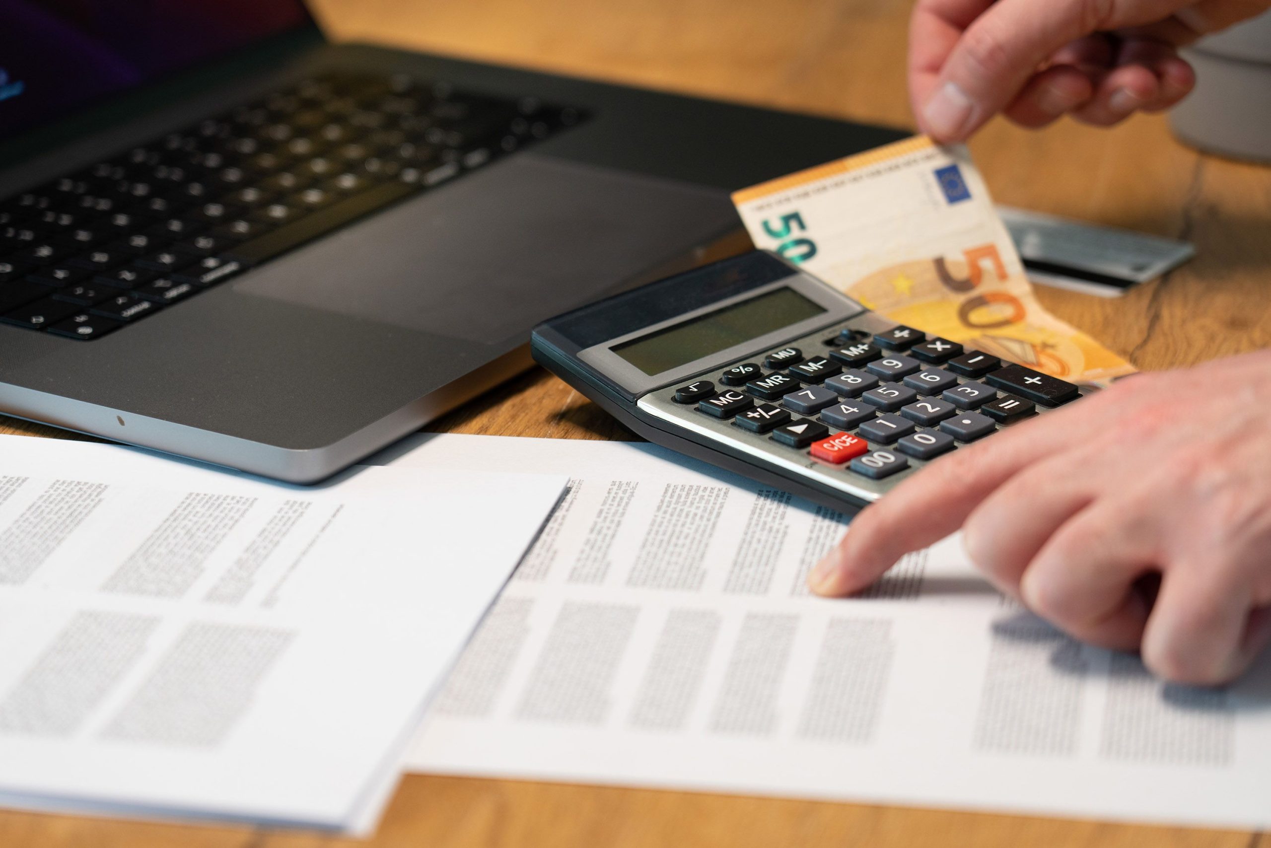 Mains utilisant calculatrice avec billets euros et ordinateur