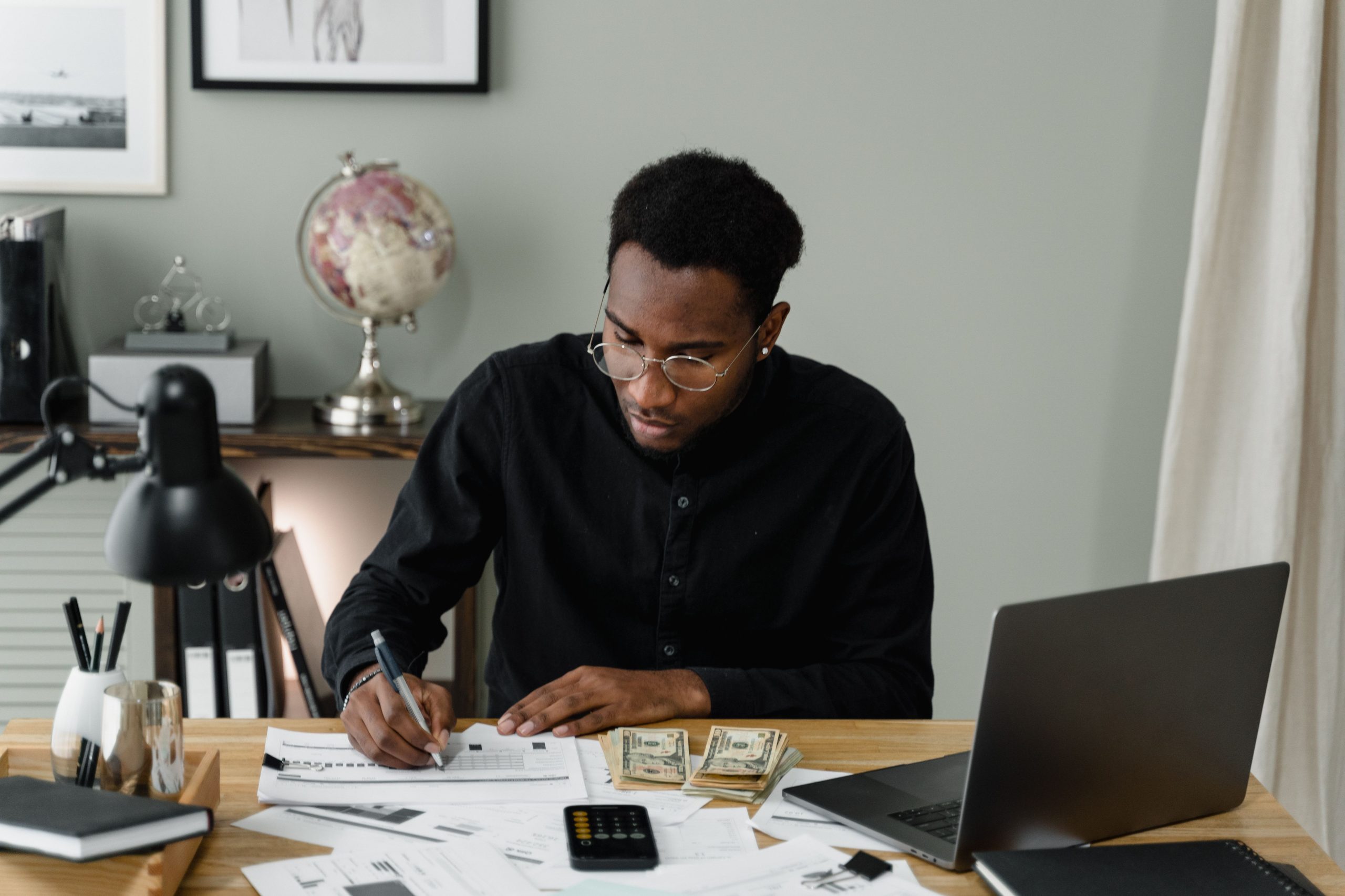 Homme calculant dépenses avec documents et ordinateur
