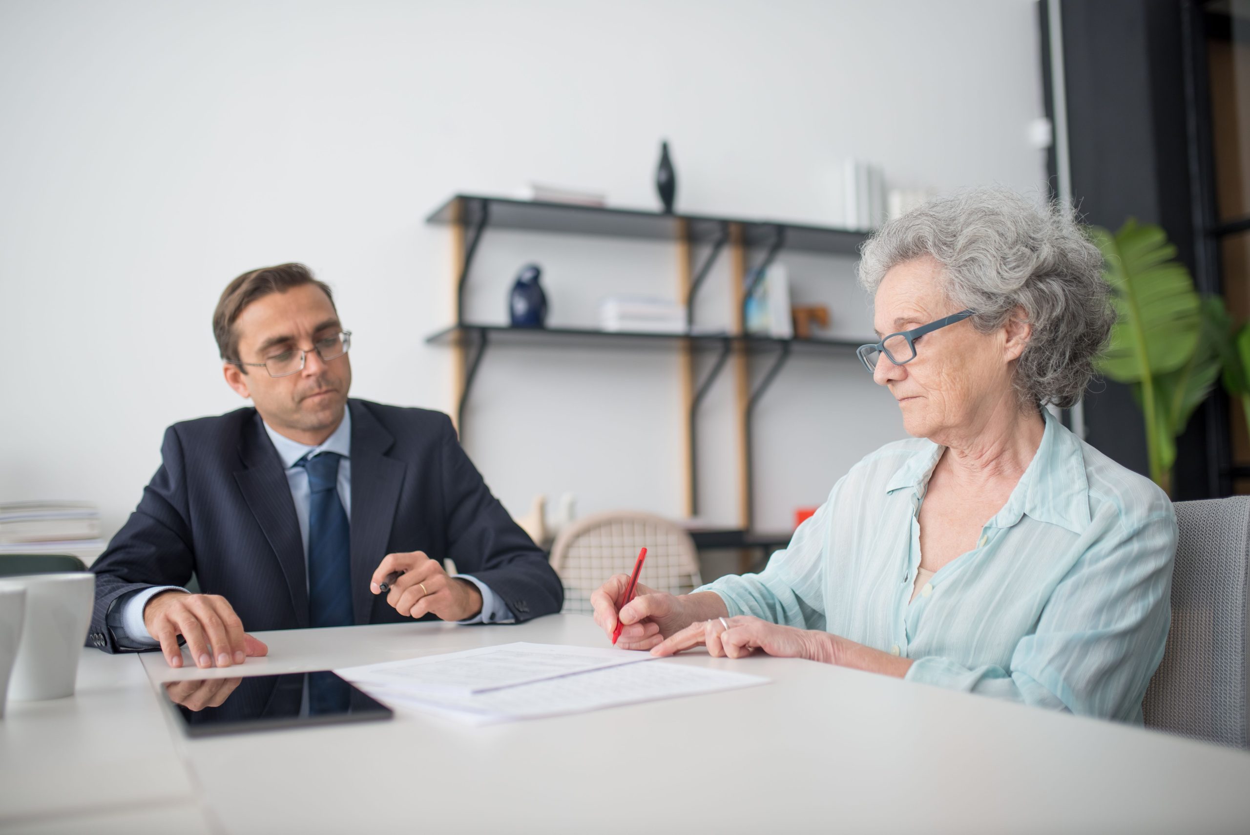 Femme senior signant des documents avec consultant