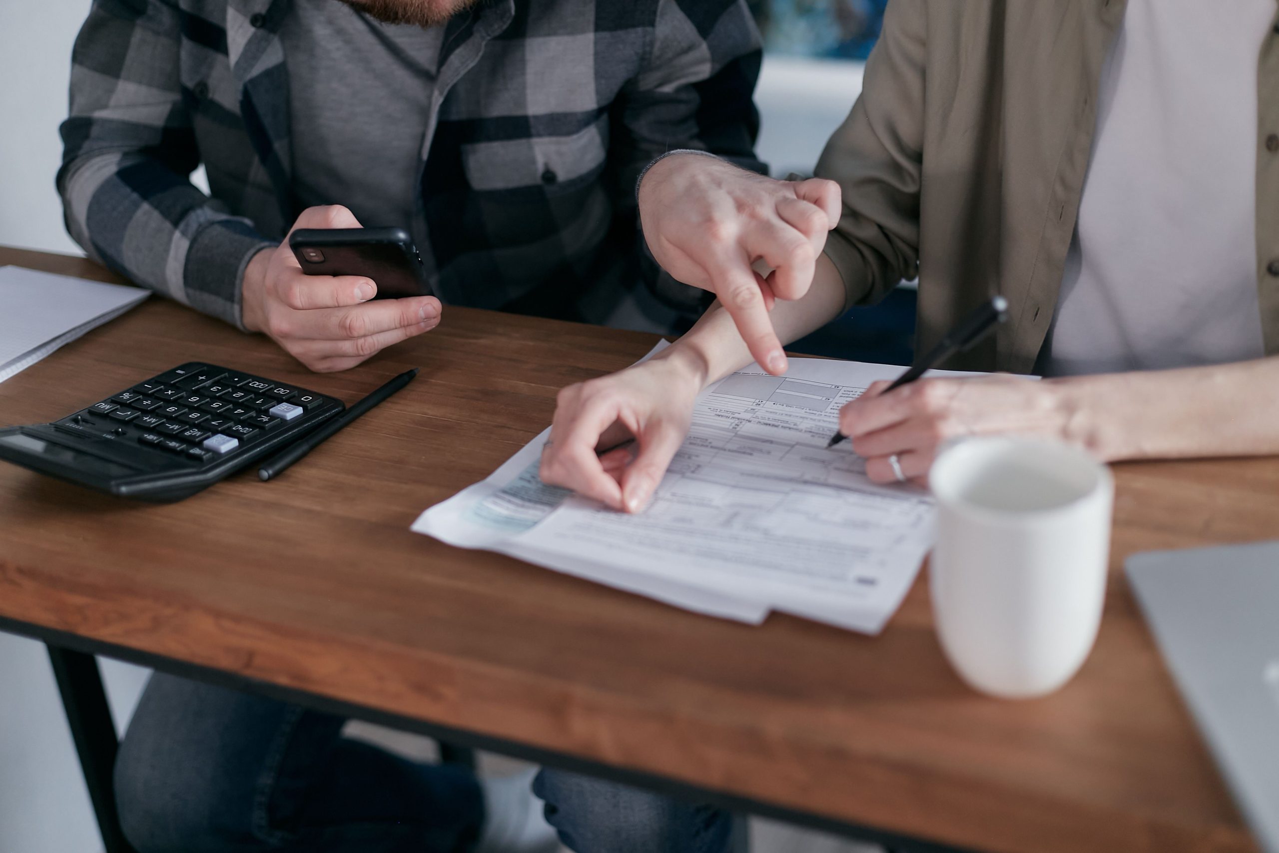Couple analysant des documents financiers avec une calculatrice