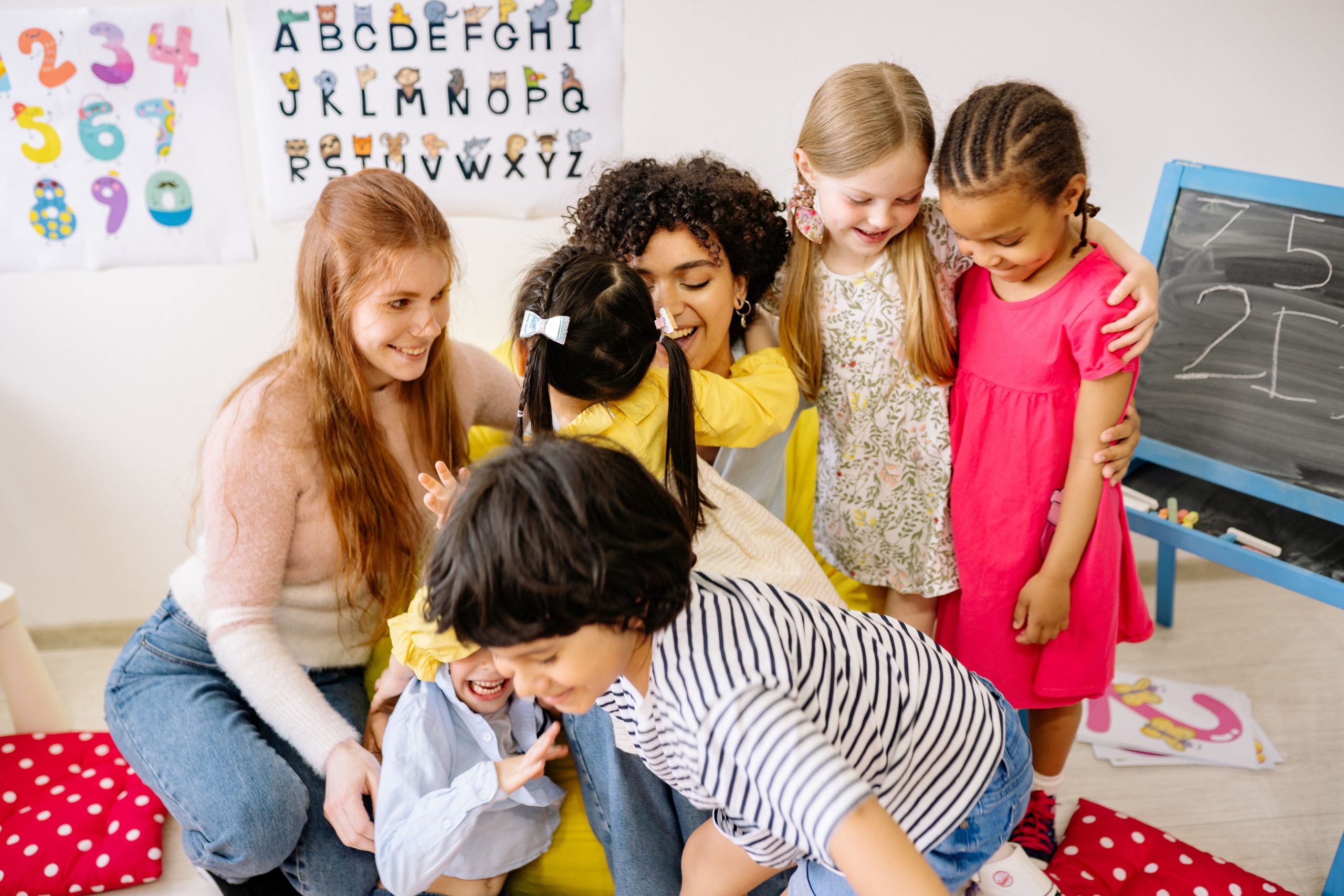Enfants et institutrice souriants en classe colorée