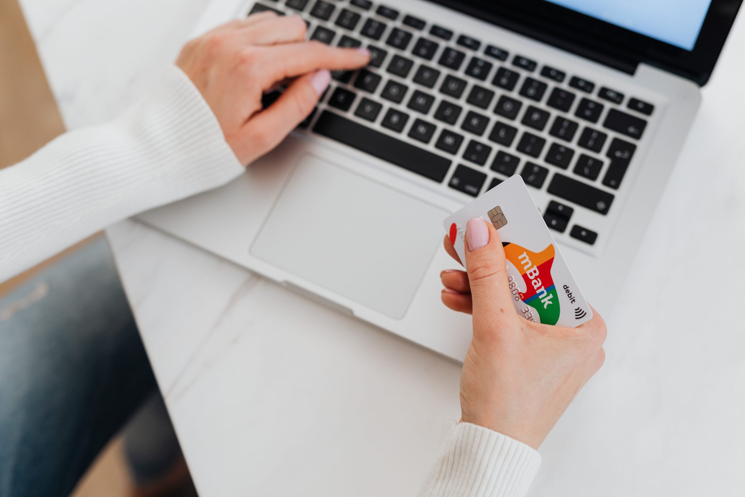 Personne tenant une carte bancaire devant un laptop