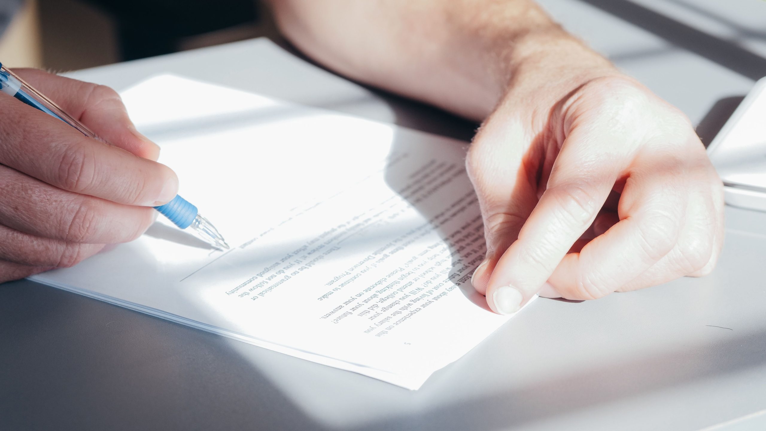 Mains signant un contrat avec stylo bleu